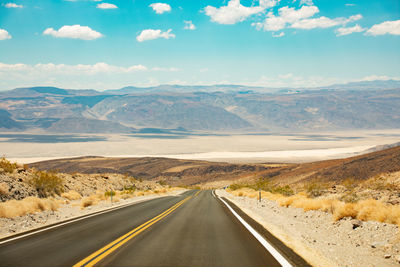 Road leading towards mountains against sky