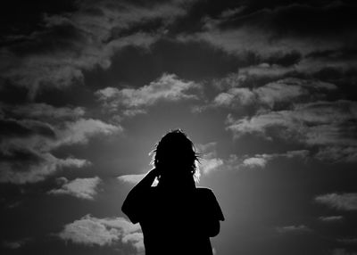 Low angle view of silhouette woman standing against sky