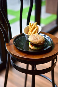 Burger with french fries in plate on wooden chair