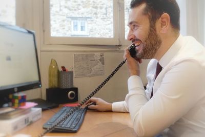 Young woman using mobile phone while sitting in office