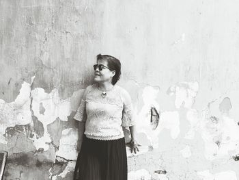 Woman in sunglasses standing against weathered wall