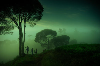 People photographing while standing on mountain at dusk