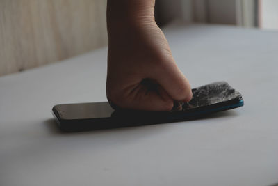 Cropped hand of person using mobile phone on table