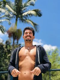 Portrait of shirtless man standing against sky