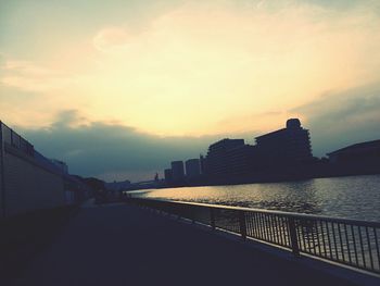 Road passing through city at sunset