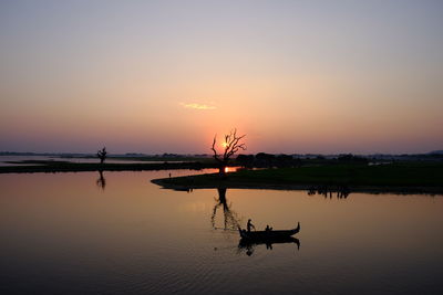 Silhouette boat in lake against sky at sunset