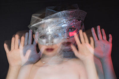 Blurred motion of woman wearing mask against black background