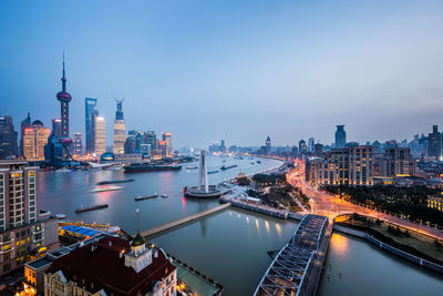 High angle view of illuminated buildings by river against sky