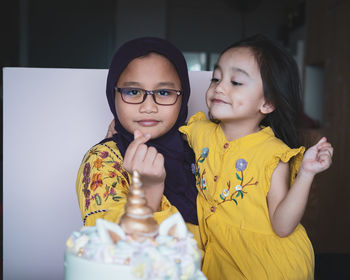 Portrait of girl gesturing heart shape while carrying sister in party