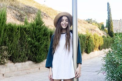 Portrait of smiling young woman standing against plants