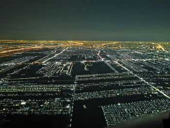 High angle view of illuminated city buildings against sky at night