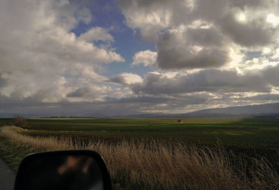 Scenic view of field against cloudy sky