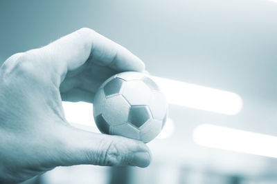 Cropped hand of person holding small soccer ball at home