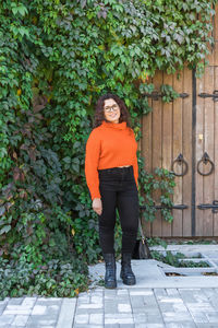 Portrait of young woman standing on footpath