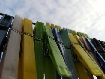 Low angle view of clothespins on clothesline against sky