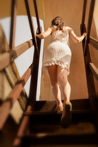 Rear view of woman climbing on staircase at home