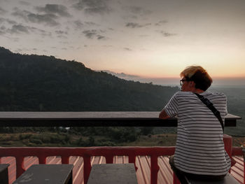 Rear view of woman standing by railing against sky