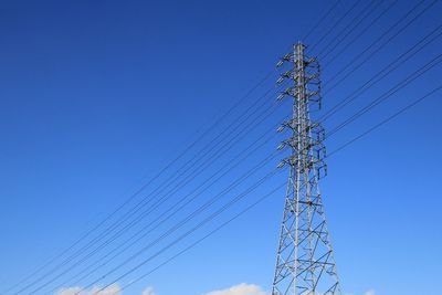 Low angle view of electricity pylon against blue sky