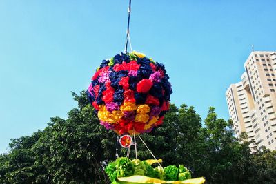 Low angle view of colorful artificial flowers decoration hanging against tree