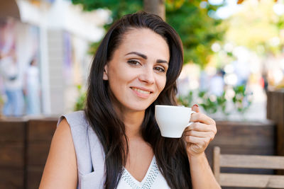 Happy smiling business brunette drinking coffee in a street cafe. coffee break