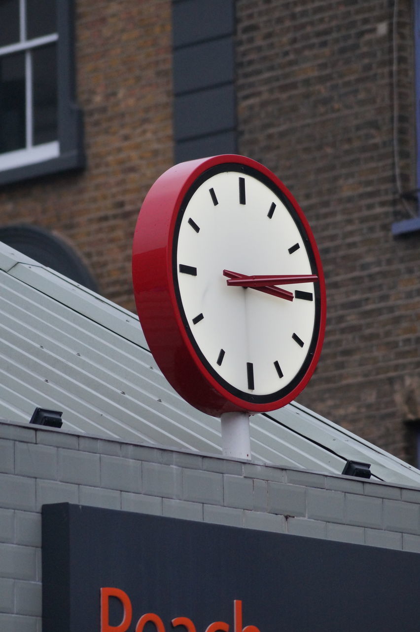 LOW ANGLE VIEW OF CLOCK ON WALL IN CITY
