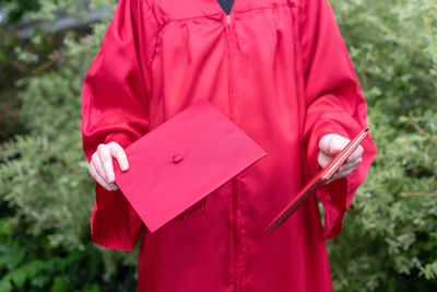 Midsection of man holding mortarboard