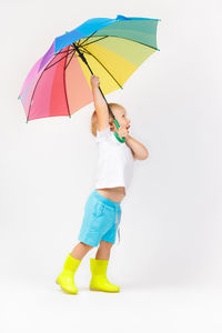 Boy holding umbrella against white background