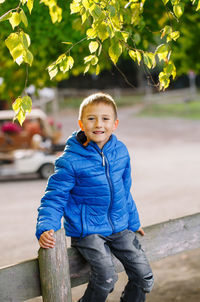 Portrait of cute boy sitting on railing