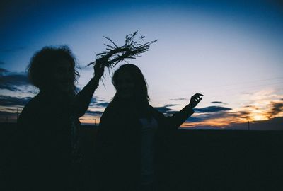 Silhouette woman standing against sky at sunset