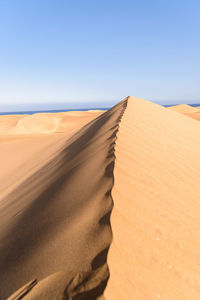 Sand dune in desert against clear sky