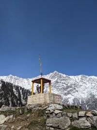 Cross on snowcapped mountains against clear blue sky