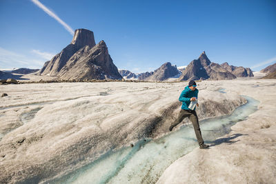 Rear view of man on rock against sky