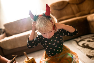 A girl with devil's horns at a halloween party at home. the child dressed up for all saints' day.