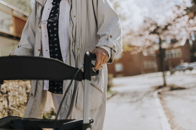 Midsection of senior woman with walker on sidewalk