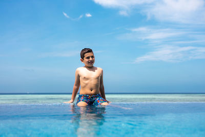 Little kid in a infinity pool near the ocean