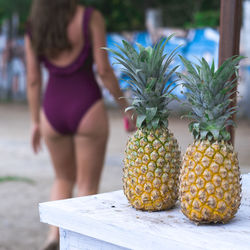 Pineapples on table with woman in bikini at background