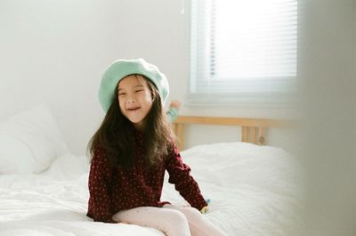 Full length of cute girl on bed at home