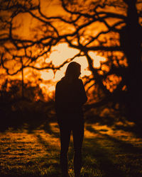 Silhouette woman standing on field during sunset