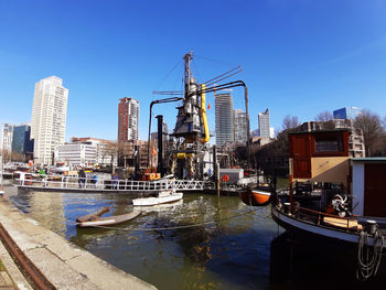 Boats in river by city against clear sky