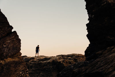 Low angle view of man standing on rock against sky