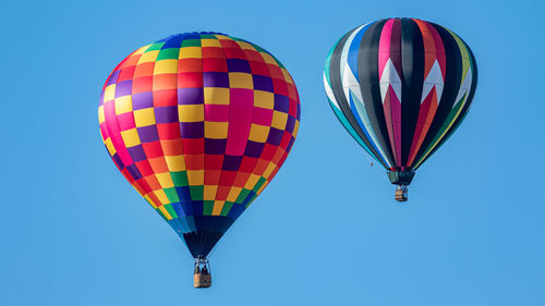 Hot air balloons float in a clear blue sky on a sunny day