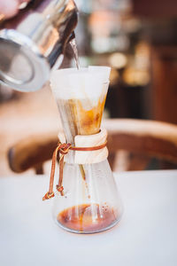 Metal container pouring water in coffee filter on table