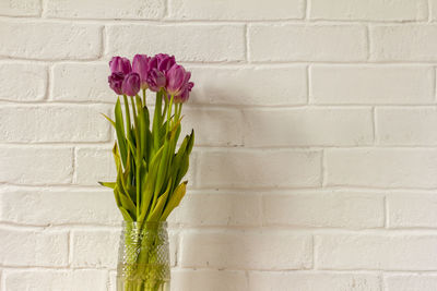 A fading bouquet of tulips in a vase on the table.