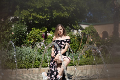 Portrait of young woman standing against trees