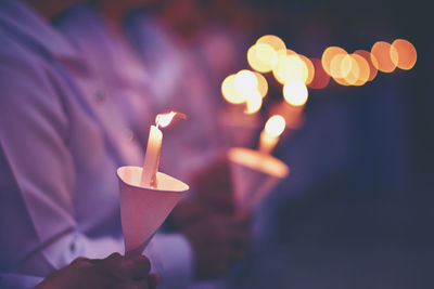 Midsection of people holding burning candles