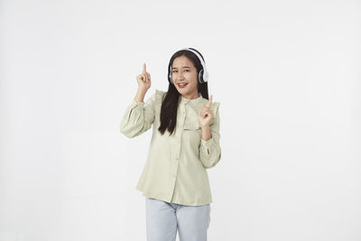 Portrait of smiling young woman standing against white background