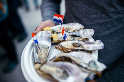 Cropped image of man holding oysters with dutch flag in plate