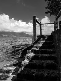 Staircase leading towards sea against sky