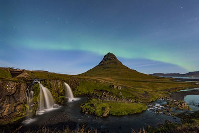 Northern lights appear over mount kirkjufell with kirkjufellfoss waterfall in iceland.