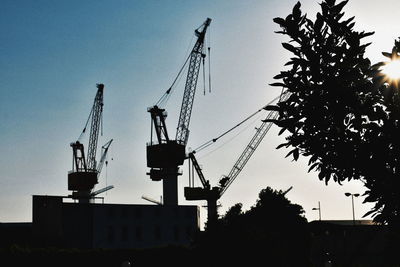 Low angle view of silhouette cranes against sky during sunset